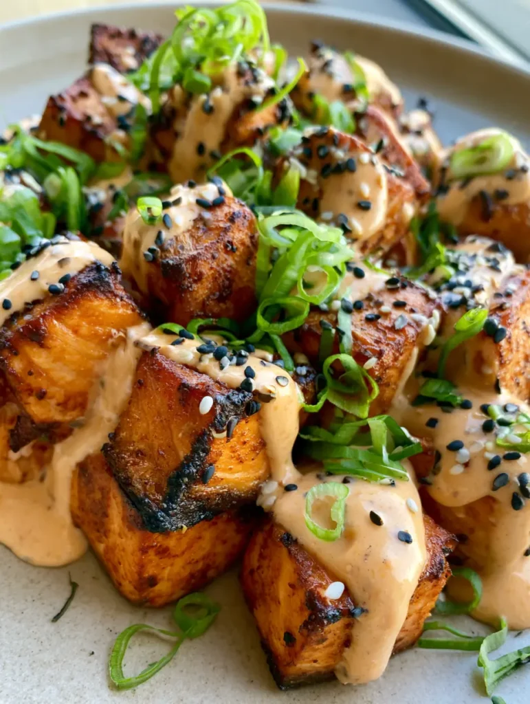 Bang Bang Lachs: Knusprige Lachs-Würfel mit cremiger Chili-Mayo 1 Detailaufnahme von saftigem Bang Bang Lachs mit schwarzem und weißem Sesam garniert.
