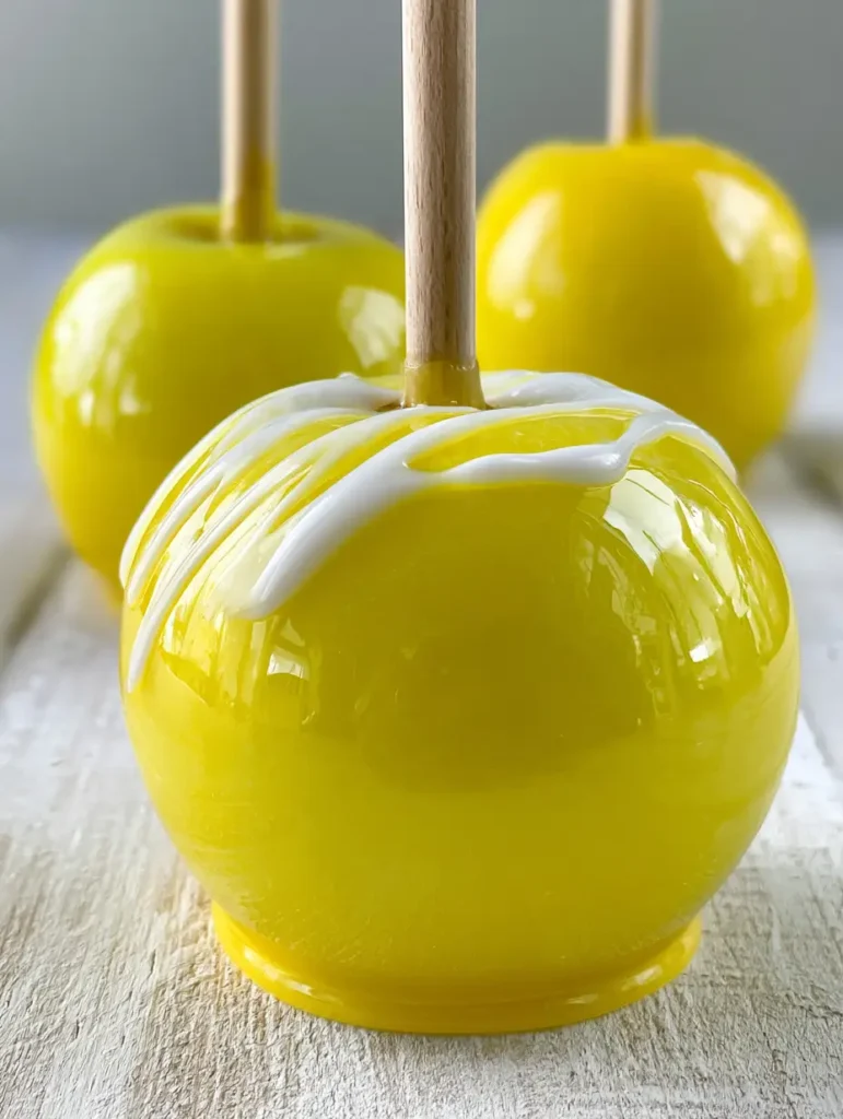 Ein kandierter Apfel mit weißem Zucker-Drizzle auf einem stabilen Holzstab.