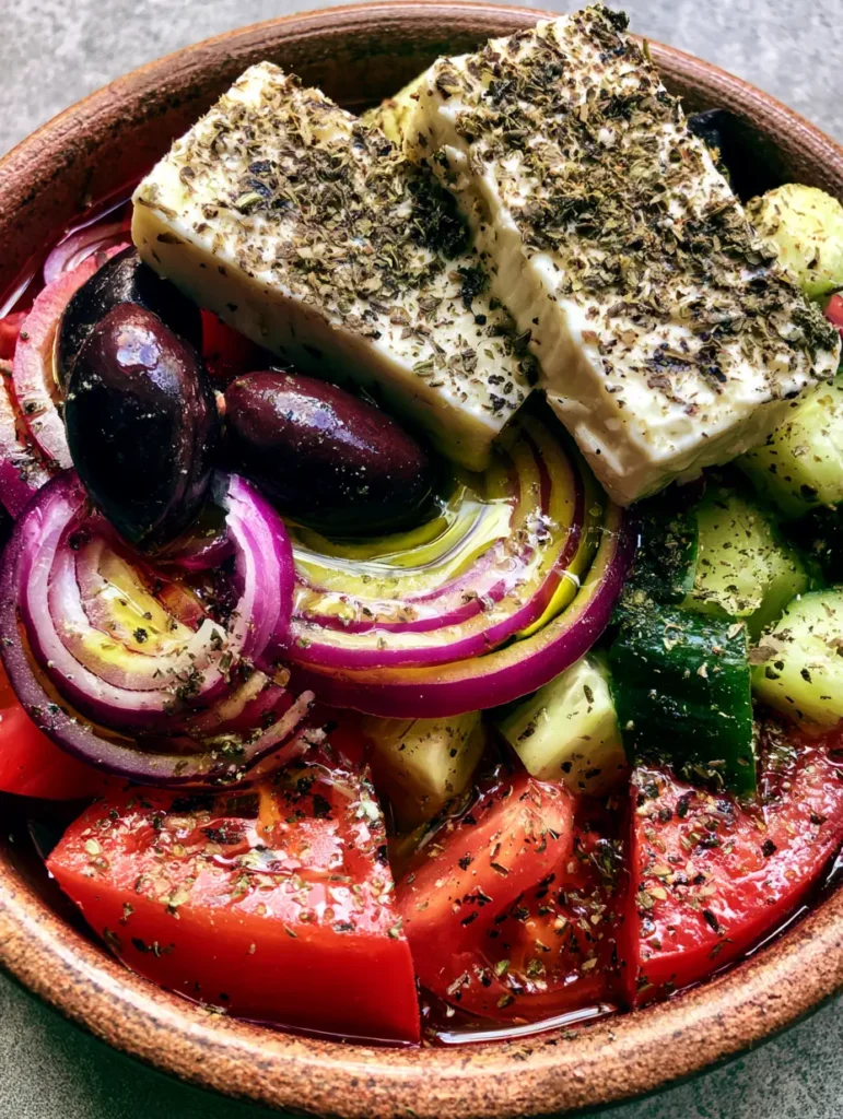 Griechischer Salat Rezept mit glänzendem Olivenöl und getrocknetem Oregano auf Feta.
