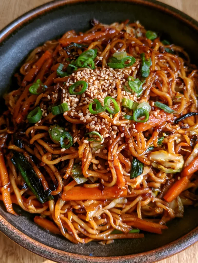 Draufsicht auf Chow Mein in einer rustikalen Schale mit frischen Frühlingszwiebeln.